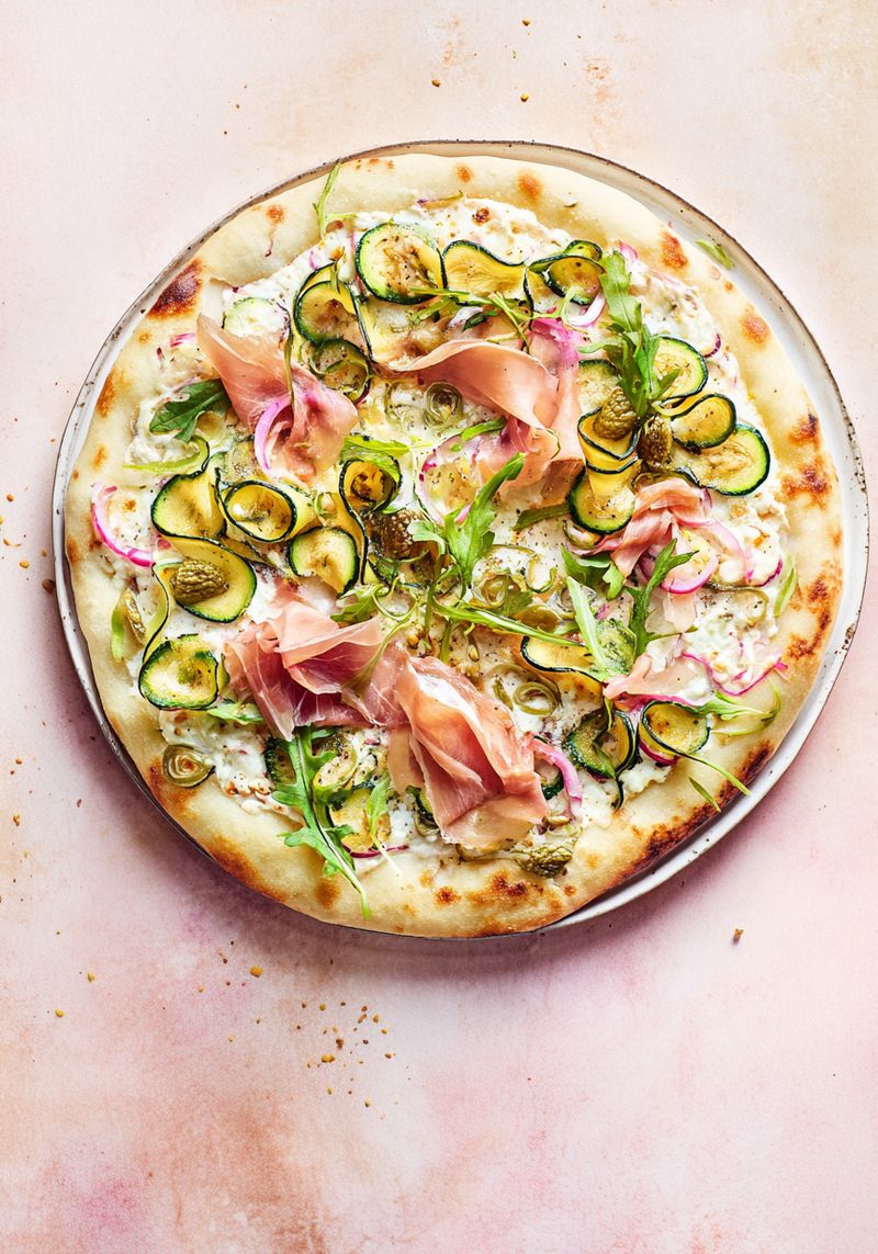 Pizza ronde blanche garnie de roquette et de jambon de Parme