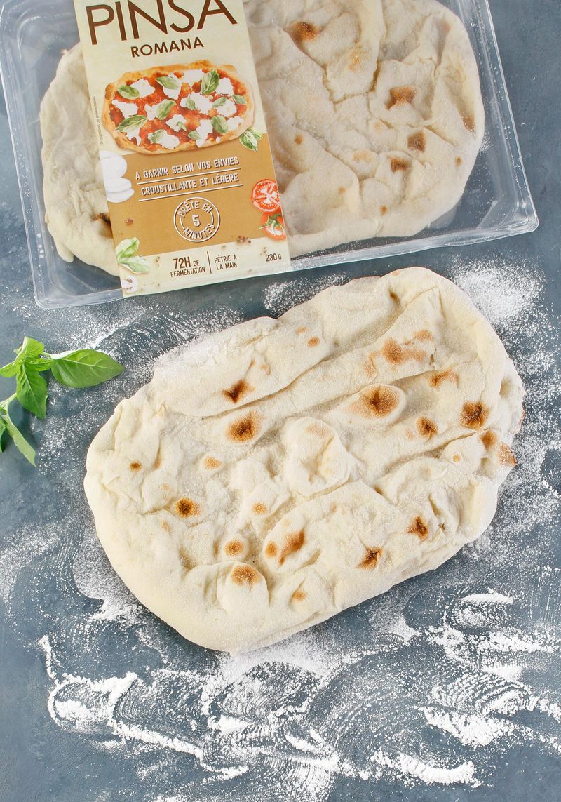 Pâte à pinsa crue, façonnée en ovale sur son papier de cuisson